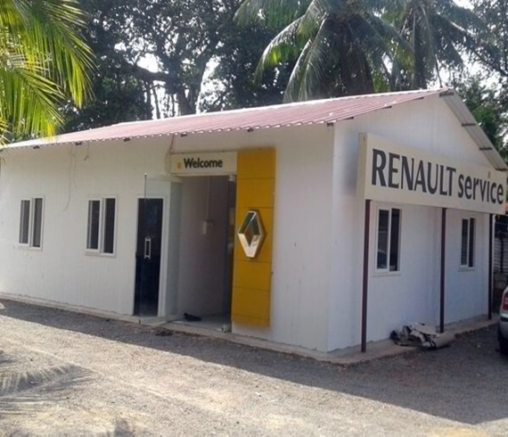  A small white Renault service building with a red roof, a yellow accent panel near the entrance, and a Welcome sign above the door